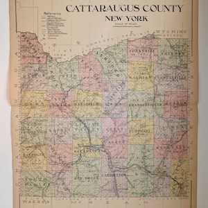 May include: A vintage map of Cattaraugus County, New York, with a scale of miles. The map features a detailed layout of towns, roads, and geographical features, with a reference key. The map is printed on aged paper.
