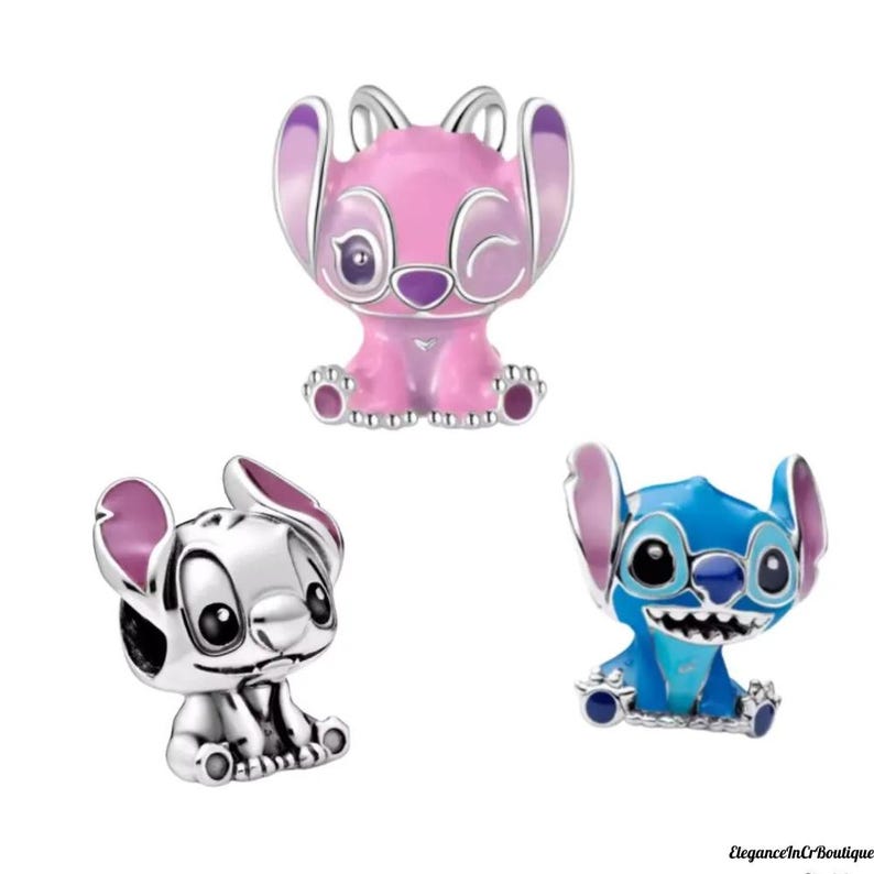 May include: Three character charms in the image. One is pink with purple accents, one is silver, and the last is blue with teal accents. All three charms have large ears and are in a sitting position. The charms are likely for a bracelet or necklace.