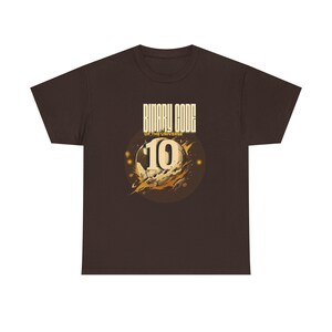 Op de afbeelding: Een bruin t-shirt met de tekst "BINARY CODE OF THE UNIVERSE" en een afbeelding van het nummer 10. Het nummer 10 staat in een cirkel met een ruimtethema.