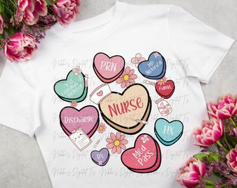 Puede incluir: Una camiseta blanca con un diseño de corazones coloridos que incluyen términos médicos como "PRN", "Discharge", "Med Pass" y "Nurse".