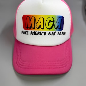 May include: A pink and white trucker hat with a rainbow-colored "Maga" logo and the text "Make America Gay Again".