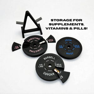 Op de afbeelding: Zwarte pillenorganizers in de vorm van halterschijven, gelabeld met namen en dagen van de week. Elke schijf heeft een sectie voor pillen. De tekst "STORAGE FOR SUPPLEMENTS, VITAMINS & PILLS!" is ook zichtbaar.