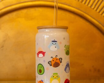May include: White reusable water bottle with a bamboo lid and a clear straw. The bottle has a colorful cartoon design with various animals and objects.