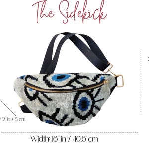 May include: A belt bag titled The Sidekick with a grey fabric featuring a black and blue eye pattern. It has a black strap and gold zipper. Dimensions are 40.6 cm wide, 15.24 cm high, and 5 cm deep. The brand name McNAT ATELIER is visible.