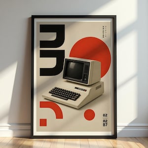 May include: A framed poster featuring a vintage computer illustration. The design includes a retro computer, a large red circle, and black geometric shapes. The poster has Japanese text and the numbers 82, A2, and B7.