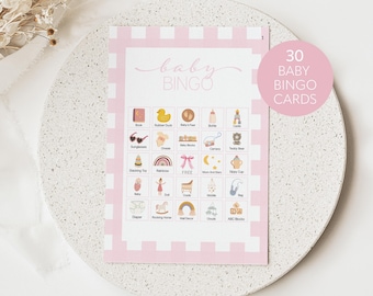 May include: A pink and white baby bingo card with 25 squares. Each square has a different baby-related item, such as a book, rubber duck, baby's feet, bottle, cradle, sunglasses, onesie, baby blocks, camera, teddy bear, stacking toy, rainbow, moon and stars, sippy cup, diaper, rocking horse, wall decor, clouds, and ABC blocks. The card says "baby bingo" at the top and "30 baby bingo cards" in the top right corner.