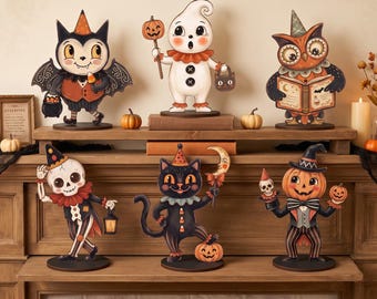 May include: A collection of six vintage-style Halloween tabletop figures including a bat, a ghost, an owl, a skeleton, a black cat, and a pumpkin-headed character. Each figure features detailed, colorful illustrations and stands on a round base.