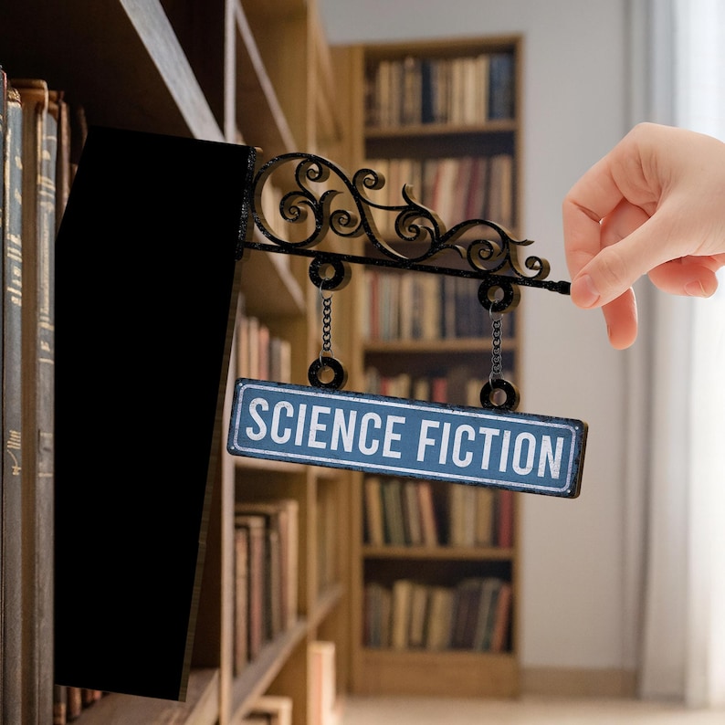 May include: A black metal bookshelf divider with an ornate scroll design and a blue sign that reads "SCIENCE FICTION." The sign hangs from chains. The background shows a library filled with books.