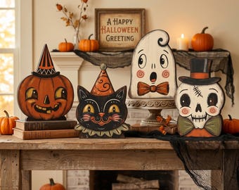 May include: Four decorative Halloween wooden cutouts featuring a jack-o'-lantern in a striped hat, a black cat in a patterned party hat, a ghost with a bowtie on a pedestal, and a skull wearing a top hat and bowtie, with a framed sign behind.