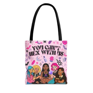 以下が含まれることがあります： 黒いハンドルが付いたピンク色のトートバッグ。「YOU CAN'T HEX WITH US」というテキストと、6人の漫画の女性のイラストが特徴です。デザインには、星、月、クリスタル、その他の神秘的なシンボルが含まれています。