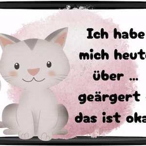 May include: A digital illustration of a gray and white cartoon cat with a pink nose and blush. The cat sits in front of a pink watercolor-style background. Text in German reads, "Ich habe mich heute &uuml;ber...ge&auml;rgert - das ist okay."