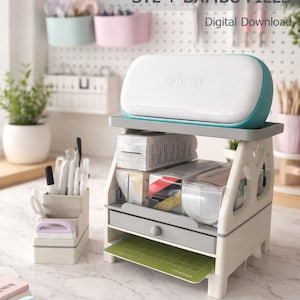 Könnte beinhalten: Eine weiß-türkisfarbene Cricut Joy Maschine steht auf einem beigen, mehrstöckigen Arbeitsplatz-Organizer. Das Gerät verfügt über eine Schublade, Ablagen für Materialrollen und einen Schlitz für eine grüne Schneidematte. Text: cricut joy workstation STL + BAMBU FILES.