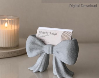 Könnte beinhalten: Ein hellgrauer, 3D-gedruckter Visitenkartenhalter in Form einer Schleife. Der Halter enthält eine weiße Visitenkarte mit dem Text MiishellyDesign. Das Bild enthält den Text business card holder STL + BAMBU FILES Digital Download.
