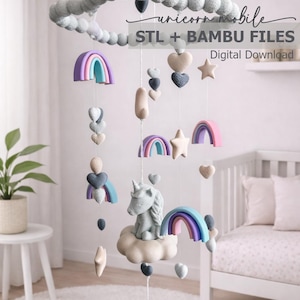 Op de afbeelding: Een grillige baby mobile met een eenhoorn, regenbogen, harten en sterren in pastelkleuren. De mobiel heeft een cirkelvormig frame met grijze pompons en is opgehangen aan touwtjes. De tekst "unicorn mobile STL + BAMBU FILES Digital Download" is zichtbaar.