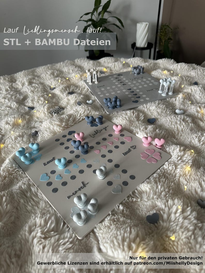 May include: Two game boards with heart-shaped game pieces in blue, pink, and white are displayed on a fluffy white surface. The boards have the words "Lauf Lieblingsmensch, lauf!" and "STL + BAMBU Dateien" printed on them.