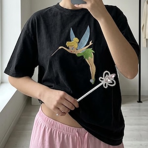 May include: A white ceramic mug with a black handle and the text "But First, Coffee" in a black, handwritten-style font. The mug is on a white surface.