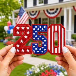 May include: A decorative patch featuring the number 250 in a patriotic theme. The number 2 is red with white stars, the number 5 is blue with white polka dots, and the number 0 features vertical red and white stripes, all with red borders.