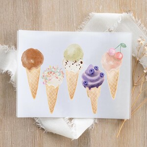 Puede incluir: Ilustración en acuarela de cinco conos de helado con diferentes sabores. Los conos presentan coberturas de chocolate, chispas, pistacho, arándanos y cerezas. La imagen está sobre un fondo blanco con una superficie de madera y una cinta blanca.