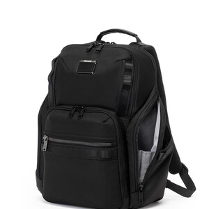 May include: Black backpack with multiple zippered compartments and a top handle. Features a small metal logo tag and a side pocket with a visible interior. The bag has adjustable shoulder straps and a sleek, modern design.