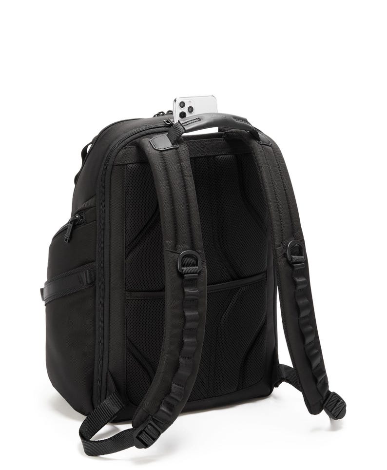 May include: Black backpack with padded shoulder straps and a mesh back panel. A smartphone rests in the top handle. The backpack has multiple compartments and a sleek, modern design, suitable for travel or everyday use.