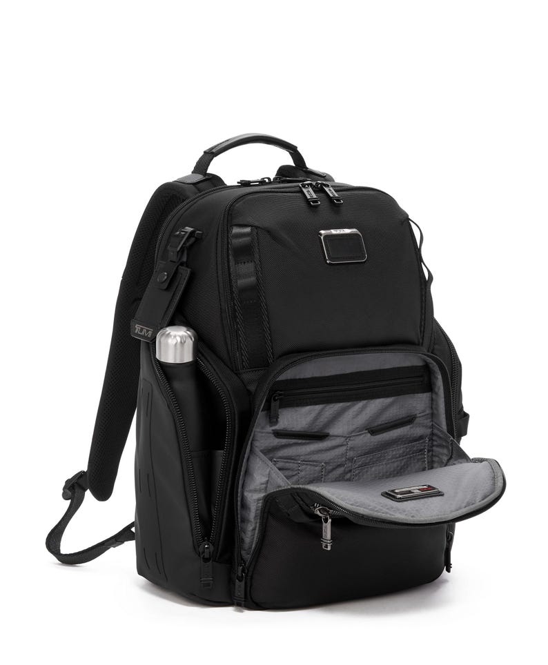May include: Black backpack with multiple compartments, a top handle, and adjustable shoulder straps. Features a side pocket with a silver water bottle and an open front compartment revealing interior pockets. The backpack has a sleek, modern design.