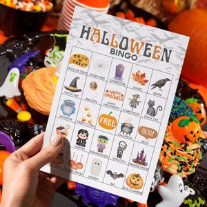 May include: A rectangular Halloween Bingo game card featuring a grid of twenty-five squares with various holiday-themed illustrations including a witch hat, pumpkin, ghost, and skeleton, with the text HALLOWEEN BINGO printed at the top.