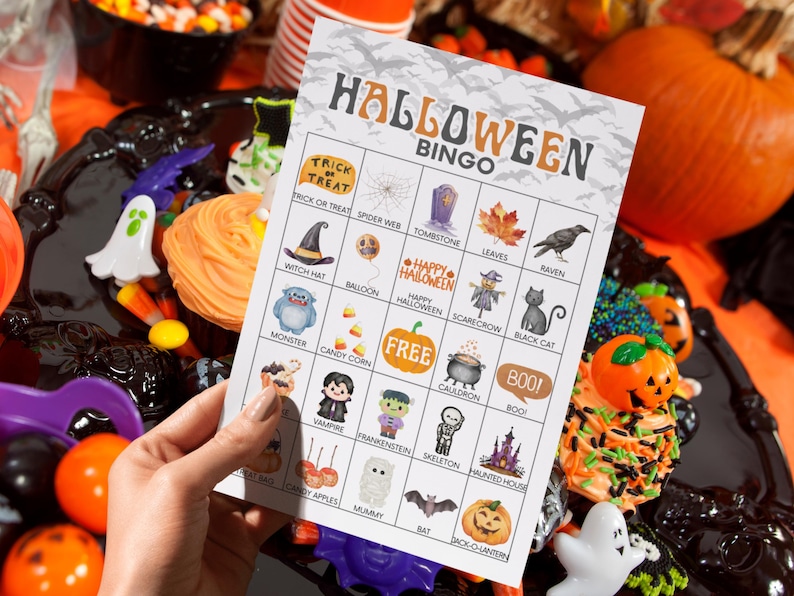 May include: A rectangular Halloween Bingo game card featuring a grid of twenty-five squares with various holiday-themed illustrations including a witch hat, pumpkin, ghost, and skeleton, with the text HALLOWEEN BINGO printed at the top.