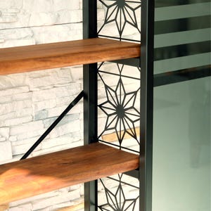 Puede incluir: Estanter&iacute;a moderna con dos estantes de madera y un marco de metal negro. El marco presenta cortes decorativos en forma de estrella. Los estantes son de color marr&oacute;n c&aacute;lido y el fondo es una pared de piedra blanca.