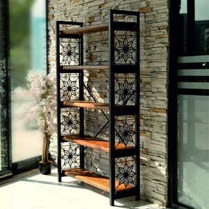 Puede incluir: Estanter&iacute;a alta de metal negro con cinco estantes de madera. Los laterales presentan dise&ntilde;os decorativos de estrellas. La estanter&iacute;a est&aacute; colocada contra una pared de piedra y junto a una ventana, mostrando un dise&ntilde;o moderno e industrial.