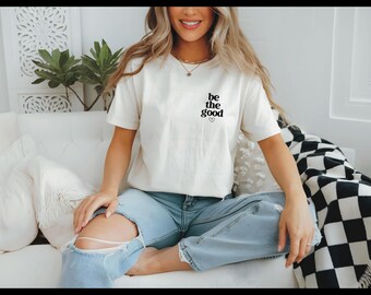 May include: A white t-shirt with the text "be the good" in black lettering and a small heart symbol.
