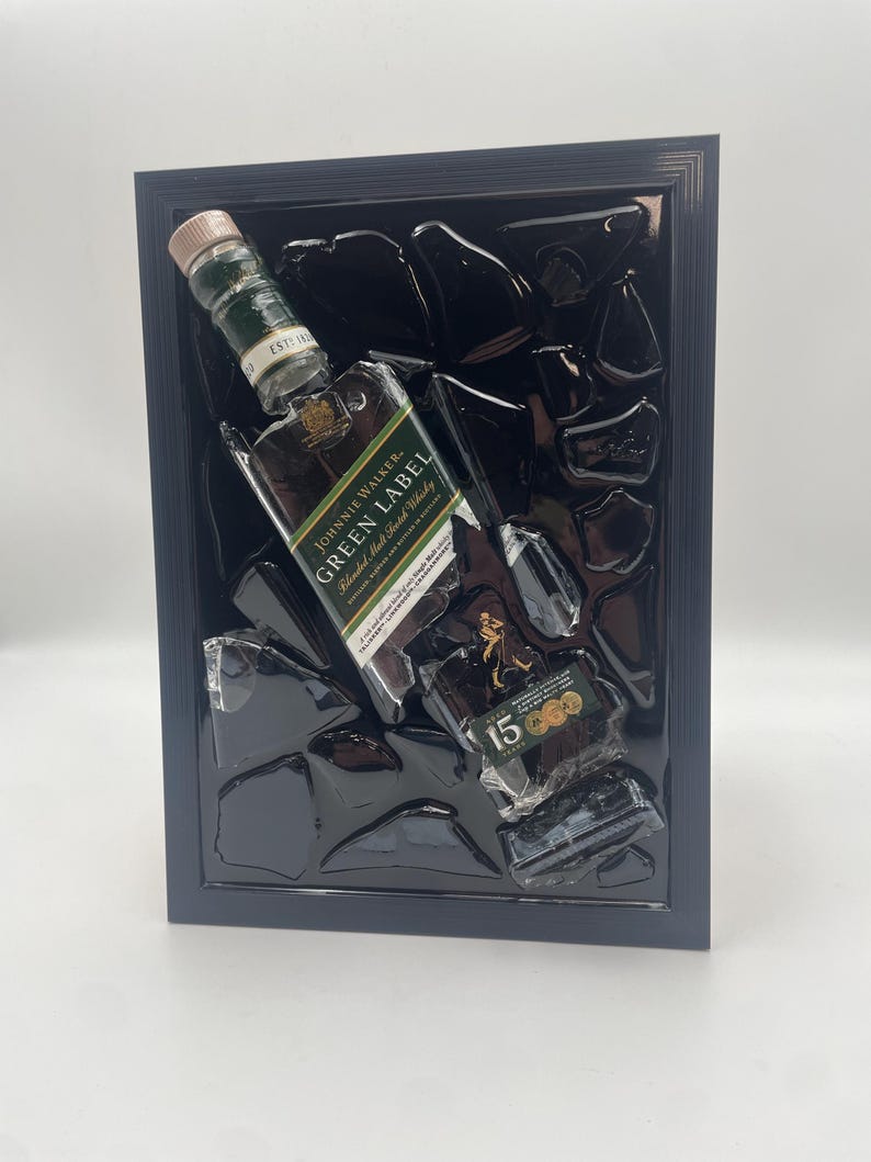 May include: Framed artwork featuring a Johnnie Walker Green Label whisky bottle. The bottle is set against a black background with abstract glass-like shapes. The label reads "Green Label Blended Malt Scotch Whisky".
