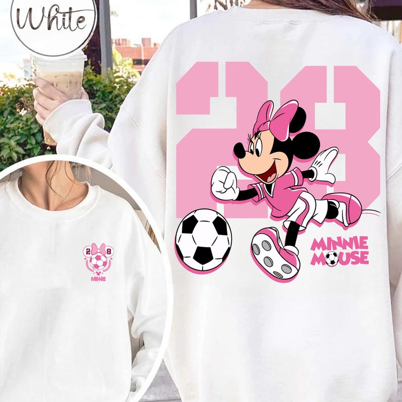 May include: White sweatshirt with a pink graphic of Minnie Mouse playing football, with the number 23 in pink. A football is also visible. The sweatshirt has the text "Minnie Mouse" in pink.