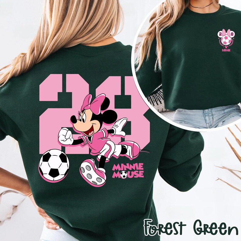 May include: Forest green sweatshirt with a pink graphic of Minnie Mouse playing football, with the number 23 in pink. The text "MINNIE MOUSE" is below the graphic. A smaller graphic of a football and the text "2028 Minnie" is on the upper right.