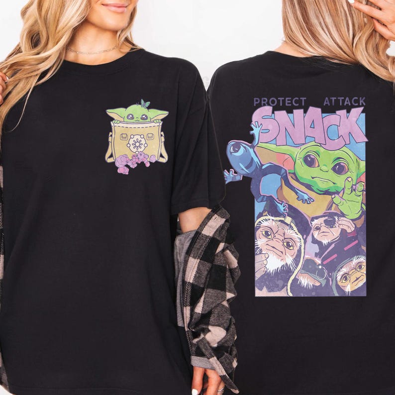 May include: Black t-shirt featuring a graphic of a green alien character in a bag with purple flowers. The back of the shirt has the words "PROTECT ATTACK SNACK" with a colorful graphic of the same character and other creatures.