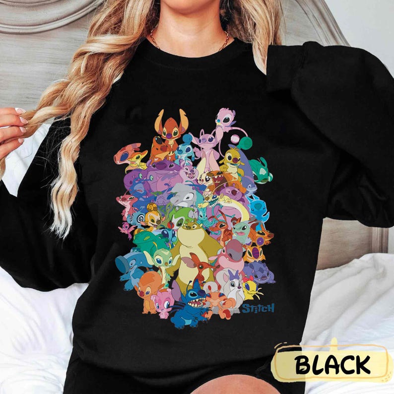 K&ouml;nnte beinhalten: Schwarzes Sweatshirt mit einem bunten Grafikdruck von Stitch und anderen Charakteren aus dem Disney-Film Lilo & Stitch. Der Text "Stitch" ist in der rechten unteren Ecke des Grafikdrucks gedruckt.