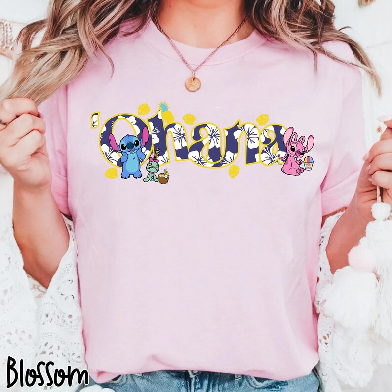 Puede incluir: Camiseta rosa claro con la palabra "Ohana" en un dise&ntilde;o floral azul con detalles amarillos. La camiseta presenta los personajes de dibujos animados Stitch y Angel, con elementos tem&aacute;ticos de Pascua. La palabra "Blossom" est&aacute; impresa en la parte inferior.