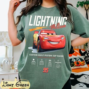 Puede incluir: Camiseta verde claro con un dise&ntilde;o de Rayo McQueen de la pel&iacute;cula Cars. El dise&ntilde;o incluye el texto "LIGHTNING McQueen" y "95", adem&aacute;s de detalles t&eacute;cnicos. La camiseta est&aacute; hecha de un material suave.