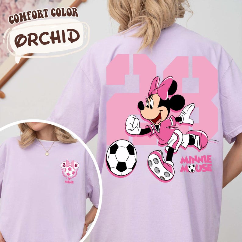 May include: Orchid-coloured t-shirt with a Minnie Mouse soccer graphic. The design includes the number 28 in pink, a football, and the text "MINNIE MOUSE". The shirt also has the text "COMFORT COLOR" and "ORCHID".