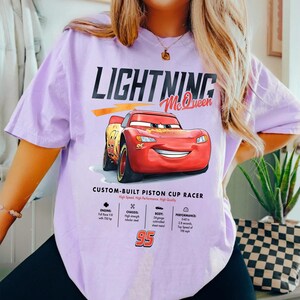 Puede incluir: Camiseta de color lila claro con un dise&ntilde;o de Rayo McQueen de la pel&iacute;cula Cars. El dise&ntilde;o incluye el texto "LIGHTNING McQueen" y detalles sobre el motor, el chasis, la carrocer&iacute;a y el rendimiento del coche. El n&uacute;mero 95 est&aacute; presente.