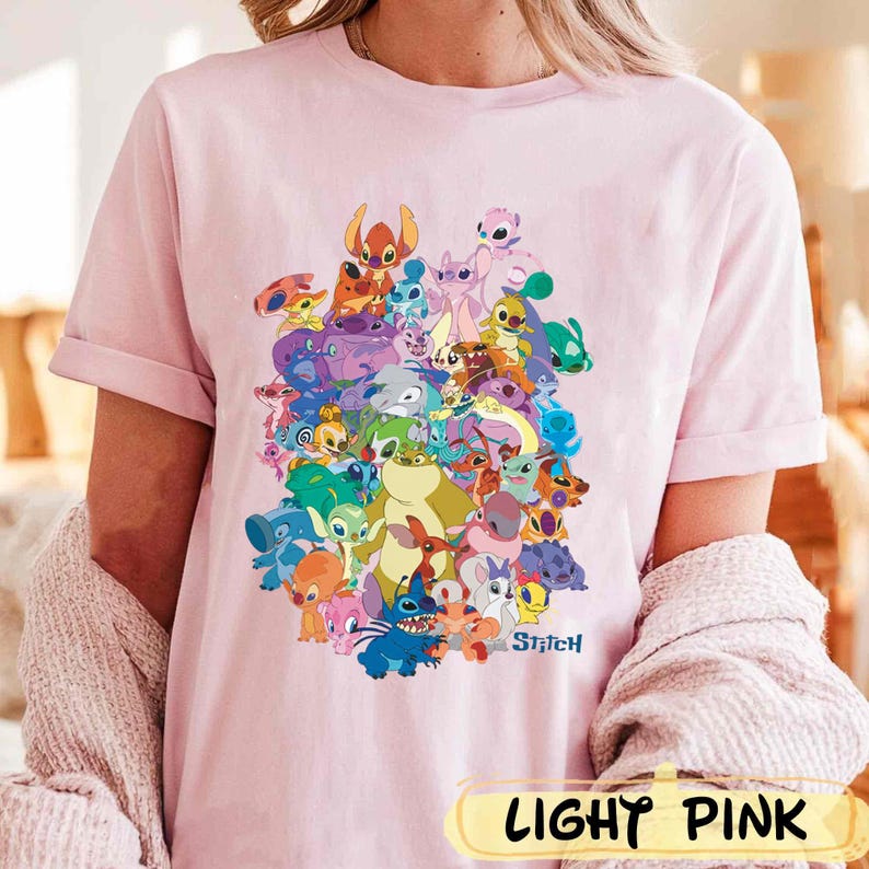 K&ouml;nnte beinhalten: Ein hellrosa T-Shirt mit einem bunten Grafikdruck von Stitch und anderen Charakteren aus dem Disney-Film Lilo & Stitch. Der Text "Stitch" ist unter dem Grafikdruck gedruckt.