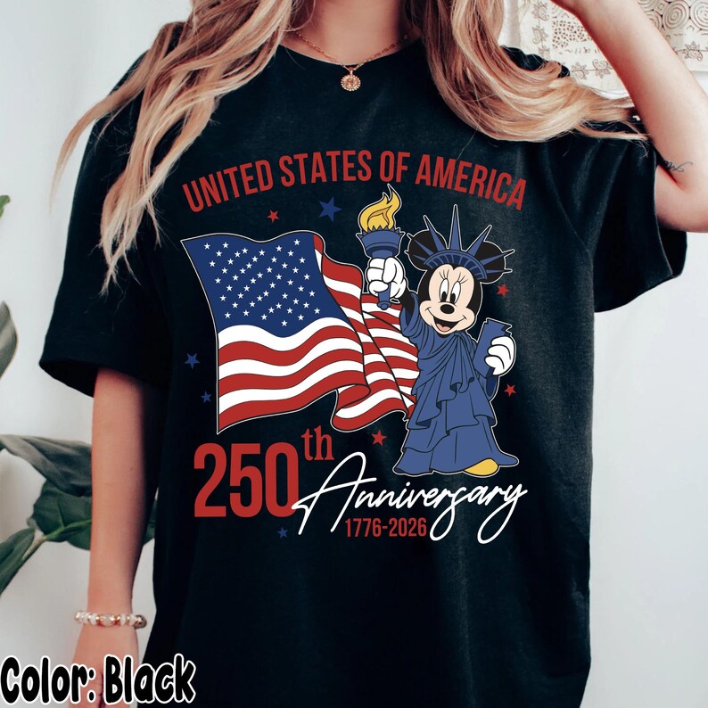 May include: Black t-shirt featuring a graphic celebrating the 250th anniversary of the United States of America. The design includes the American flag, the Statue of Liberty as Minnie Mouse, and the text "United States of America" and "250th Anniversary 1776-2026."
