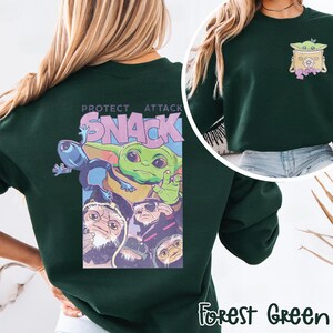 May include: Forest green sweatshirt featuring a graphic of a green alien character with the text "PROTECT ATTACK SNACK". The design includes other alien characters. A smaller graphic of the alien character is on the upper right chest.