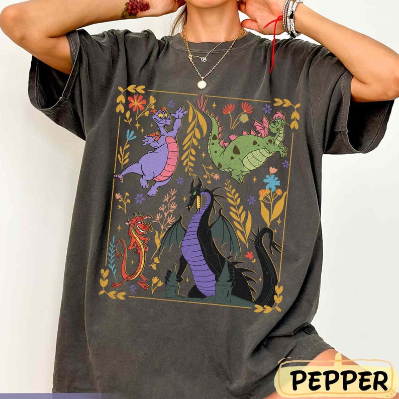 May include: Dark gray t-shirt featuring a colorful dragon graphic within a gold-lined square. The design includes a purple dragon, a green dragon, a red dragon, and a black dragon. The word "PEPPER" is printed at the bottom.