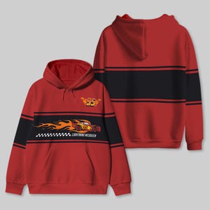 以下が含まれることがあります： 黒のストライプと炎の赤いレーシングカーのグラフィック、そして「ライトニング・マックィーン」の文字と「95」の数字がプリントされた赤いフード付きスウェットシャツ。