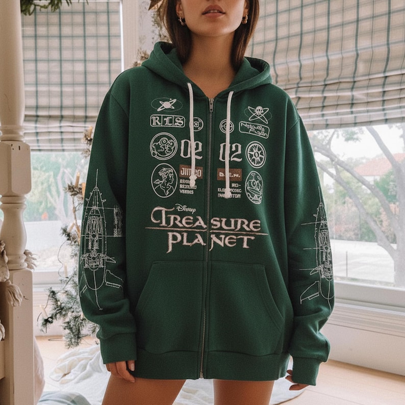 May include: A dark green zip-up hoodie featuring the text "Disney Treasure Planet" in white. The hoodie has various white graphic patches and a ship blueprint design on the sleeves. It has a drawstring hood and a front pocket.