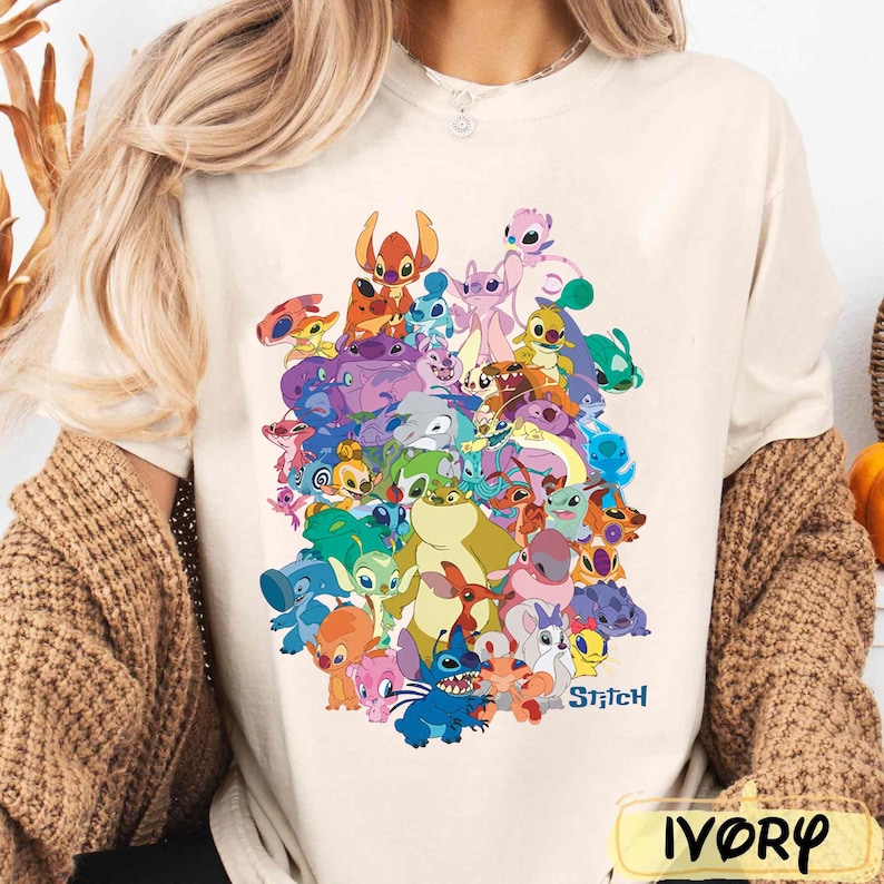K&ouml;nnte beinhalten: Ein wei&szlig;es T-Shirt mit einem bunten Grafikdruck von Stitch und anderen Charakteren aus dem Disney-Film Lilo & Stitch. Der Text "Stitch" ist in Schwarz am unteren Rand des Grafikdrucks gedruckt.