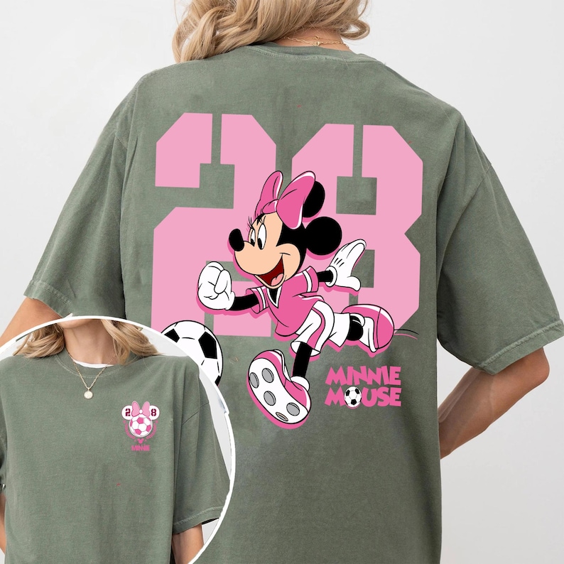 May include: An olive green t-shirt with a pink graphic of Minnie Mouse playing football, with the number 23 in pink. The words "MINNIE MOUSE" are printed below the character. A smaller image of the design is on the front.