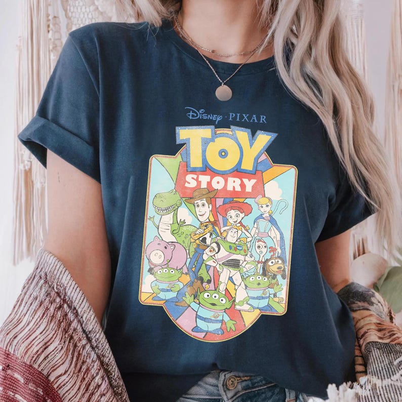 Puede incluir: Camiseta azul marino con el logotipo y los personajes de Disney Pixar Toy Story. El gr&aacute;fico incluye a Woody, Buzz Lightyear y otros personajes de la pel&iacute;cula animada. La camiseta tiene mangas enrolladas y cuello redondo.
