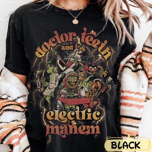 May include: Black t-shirt with a graphic of Doctor Teeth and the Electric Mayhem band from The Muppets. The design shows the band members playing instruments, with lightning and the band's name in a vintage style.