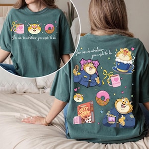 May include: Teal-colored graphic t-shirt featuring a cartoon leopard design with a donut, coffee cup, and the text "You can be whatever you wish to be." The back of the shirt has additional leopard illustrations and text.